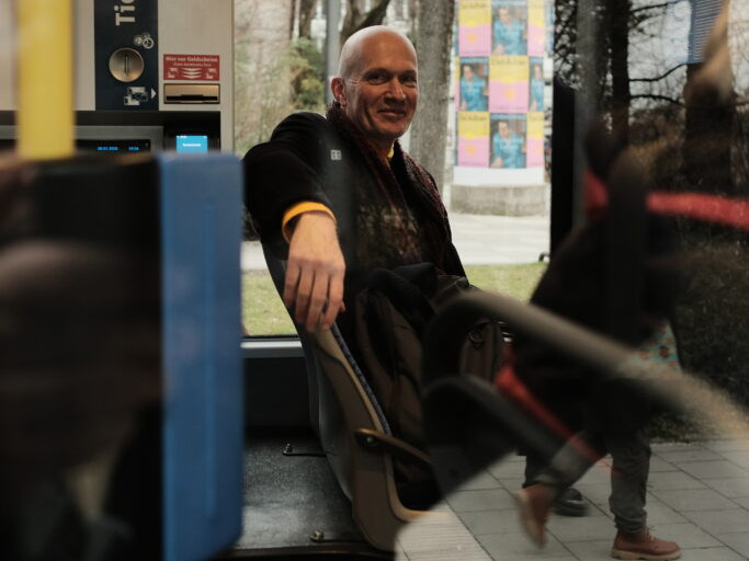 KI generiert: Ein Esel steht auf sandigem Boden in einem Gehege, und eine Karotte hängt an einem Stab vor ihm. Der Esel scheint die Karotte anzuschauen, die außerhalb seiner Reichweite ist.